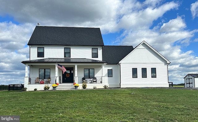 modern farmhouse featuring covered porch, metal roof, a front lawn, and a standing seam roof