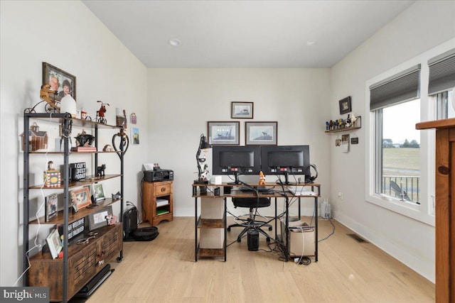 home office with visible vents, light wood-style flooring, and baseboards