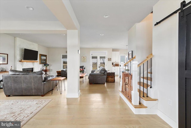 entryway with a fireplace, light wood finished floors, recessed lighting, a barn door, and stairs