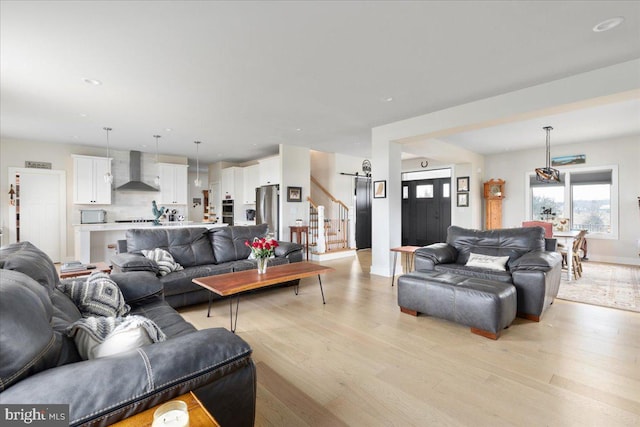 living area featuring baseboards, light wood finished floors, and stairs