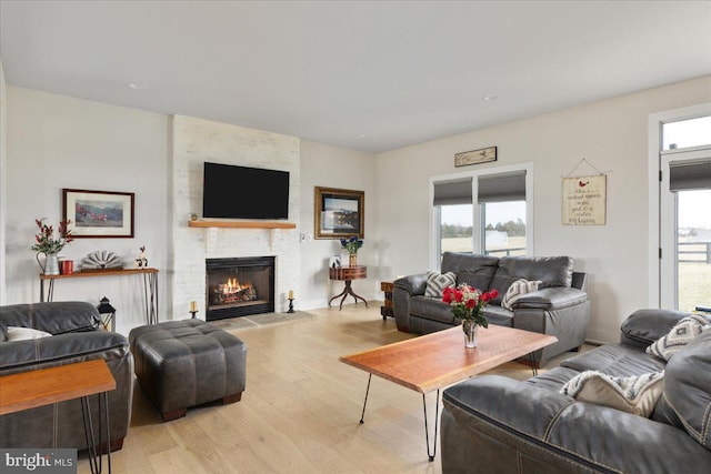 living room featuring light wood-type flooring, a fireplace, and plenty of natural light