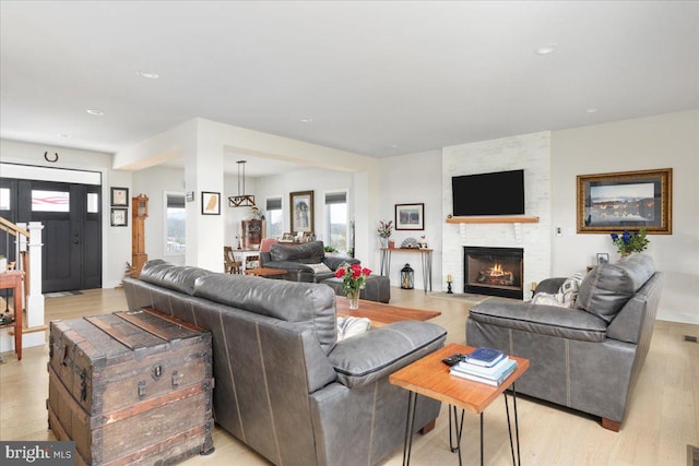 living room with recessed lighting, a fireplace, and light wood-style flooring