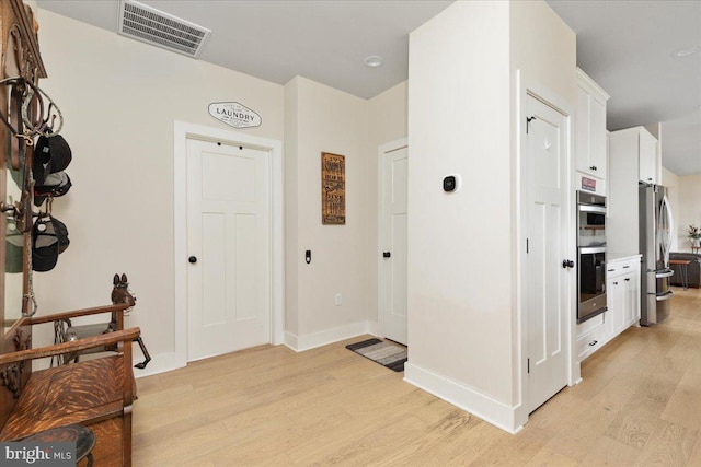 foyer entrance featuring light wood-style flooring, visible vents, and baseboards