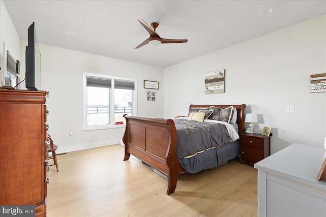 bedroom with baseboards, a ceiling fan, and light wood-style floors