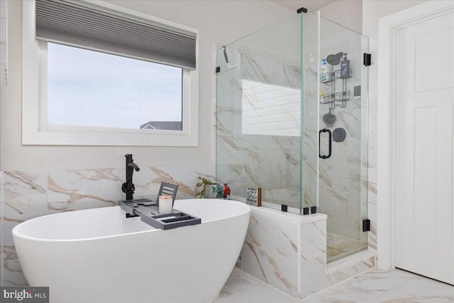 full bathroom with marble finish floor, a freestanding bath, tile walls, and a marble finish shower