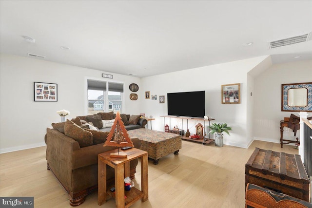 living room with baseboards, visible vents, and light wood-style floors