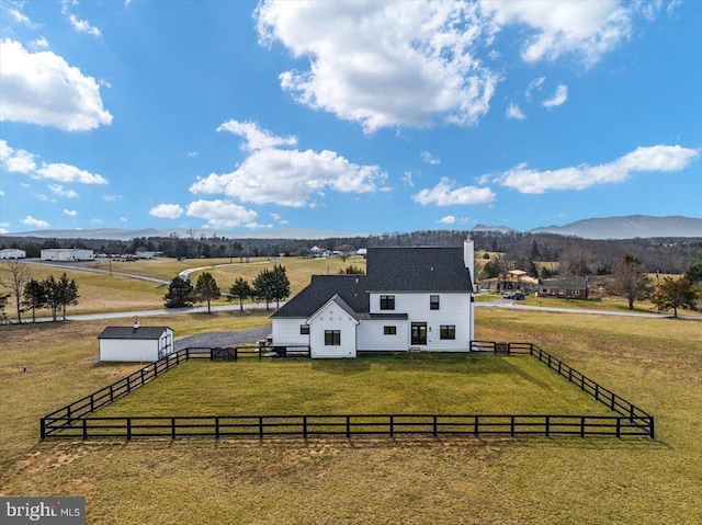 exterior space with a rural view, a front yard, fence, and a mountain view