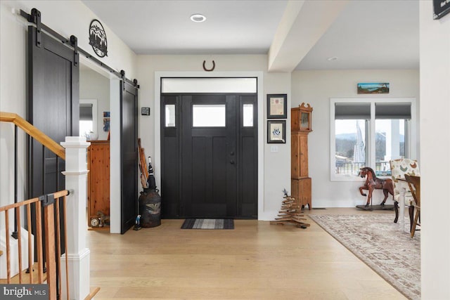 foyer entrance featuring stairs, light wood-style flooring, and a barn door