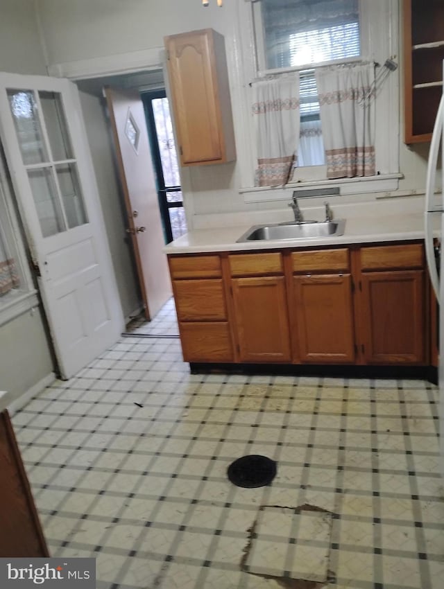 kitchen with brown cabinetry, a healthy amount of sunlight, light countertops, and a sink