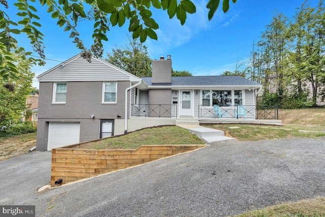 view of front of property with a garage, covered porch, and a front yard