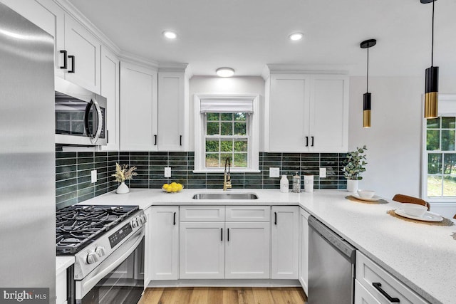 kitchen featuring sink, stainless steel appliances, decorative backsplash, white cabinets, and decorative light fixtures