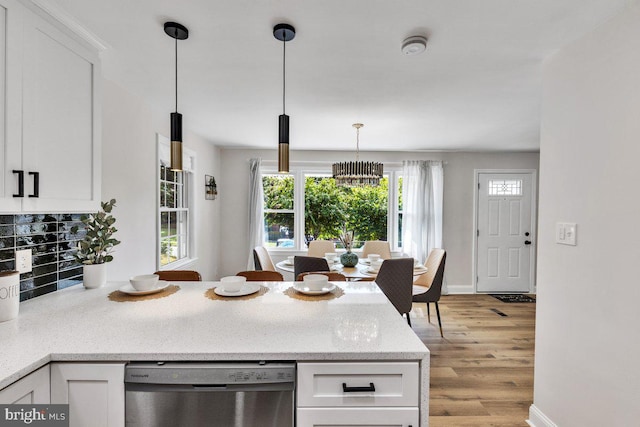 kitchen featuring hanging light fixtures, white cabinetry, stainless steel dishwasher, and light wood-type flooring