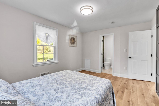 bedroom with ensuite bathroom and light wood-type flooring