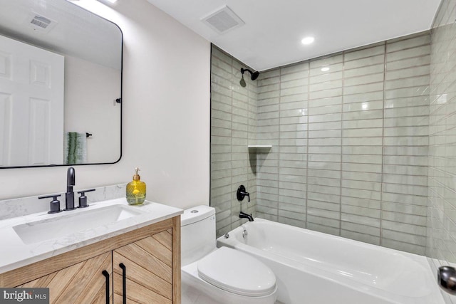 full bathroom featuring tiled shower / bath, vanity, and toilet