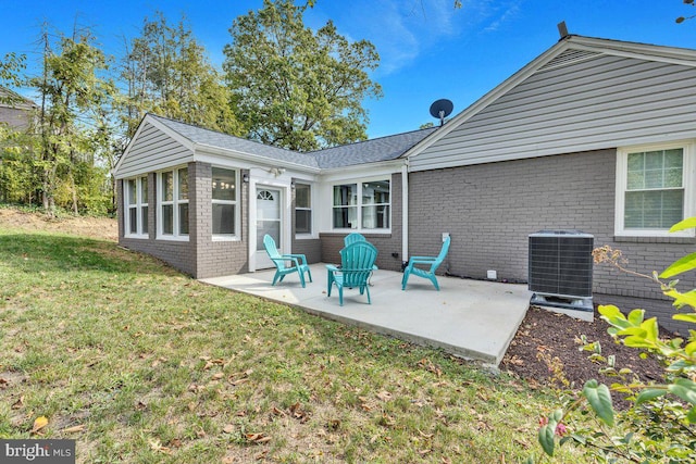 rear view of property with cooling unit, a yard, and a patio area