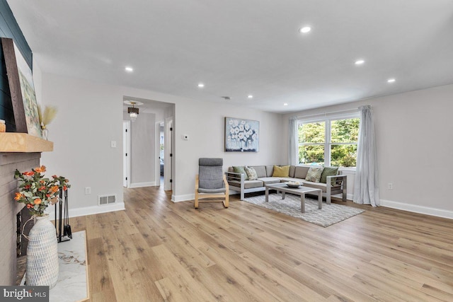 living room with a high end fireplace and light hardwood / wood-style flooring