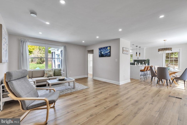 living room featuring a chandelier, a wealth of natural light, and light hardwood / wood-style floors