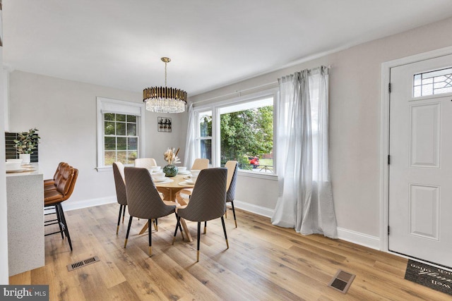 dining area with plenty of natural light, a notable chandelier, and light hardwood / wood-style floors