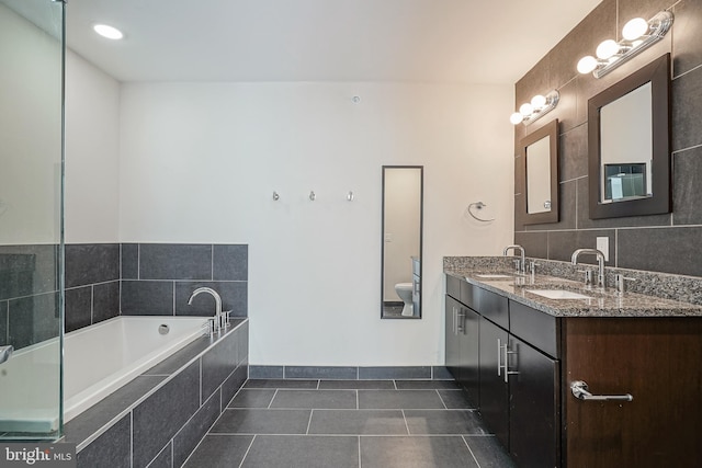 bathroom featuring tile patterned flooring, vanity, tiled bath, and toilet