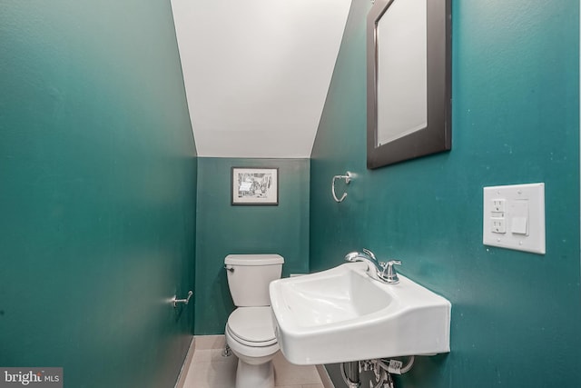 bathroom with lofted ceiling, tile patterned floors, toilet, and sink