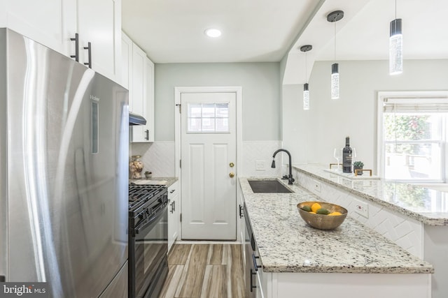 kitchen featuring sink, gas stove, white cabinetry, decorative light fixtures, and refrigerator