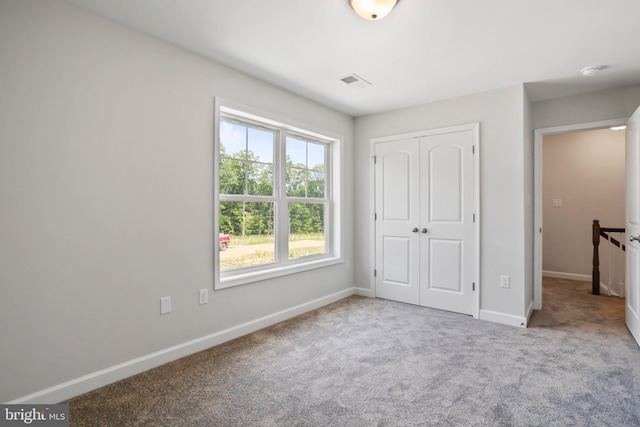 unfurnished bedroom with light carpet and a closet