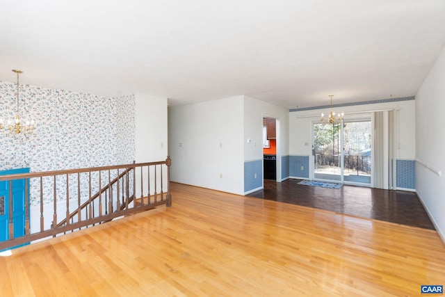 unfurnished room with an inviting chandelier and hardwood / wood-style floors