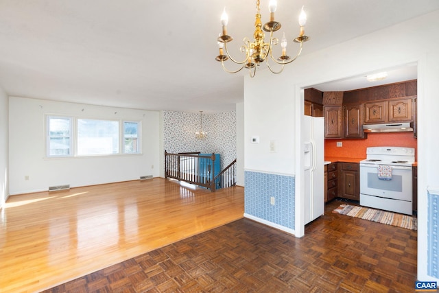 kitchen with white appliances, a chandelier, and dark parquet floors