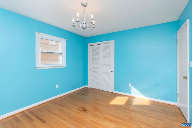 unfurnished bedroom featuring a notable chandelier, hardwood / wood-style flooring, and a closet