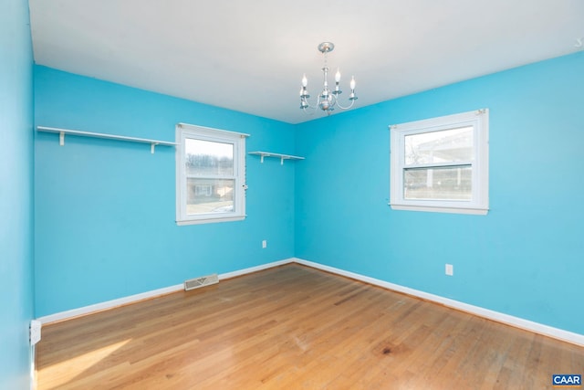 empty room featuring hardwood / wood-style floors and a notable chandelier