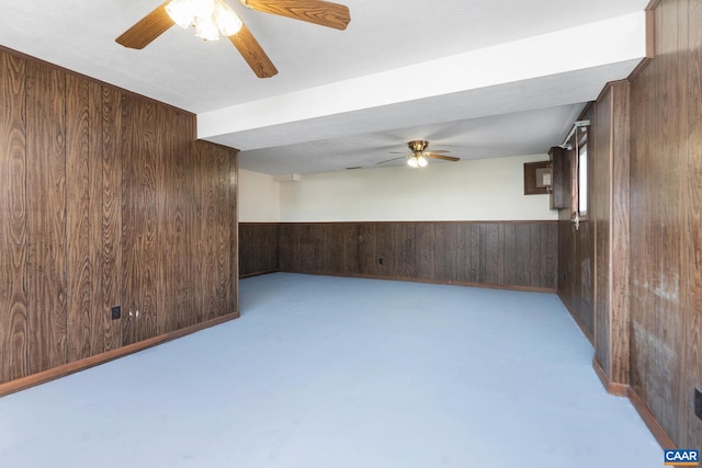 empty room featuring ceiling fan and wood walls