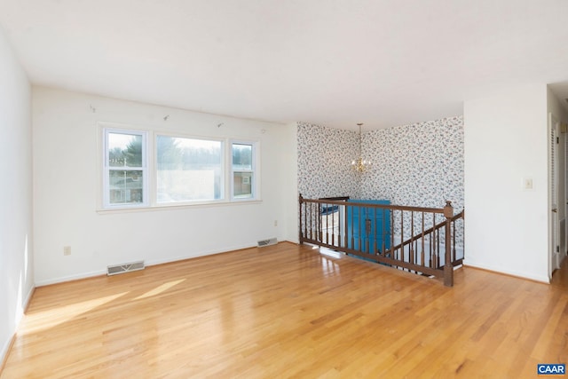 unfurnished room with hardwood / wood-style floors and a notable chandelier