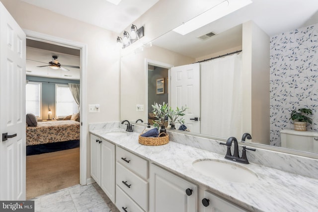 bathroom with a skylight, vanity, ceiling fan, and toilet