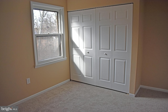 unfurnished bedroom with light colored carpet and a closet