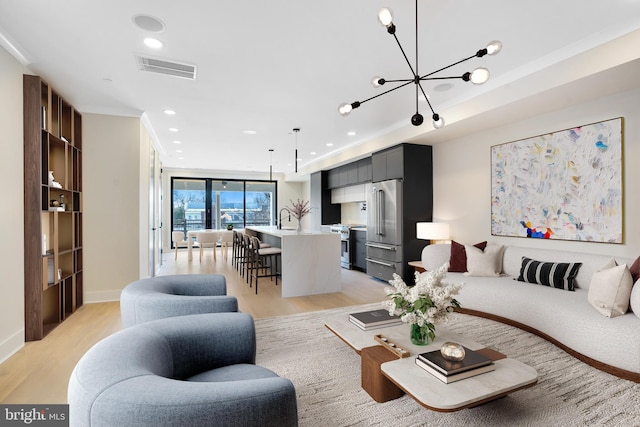 living room with a notable chandelier, recessed lighting, visible vents, baseboards, and light wood finished floors