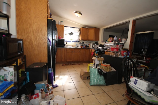 kitchen featuring lofted ceiling, light tile patterned floors, and black appliances