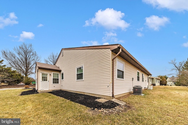 view of side of home featuring cooling unit and a yard