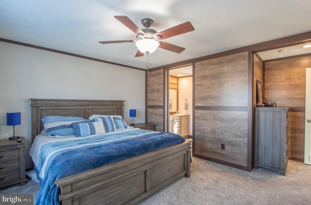 bedroom with crown molding, ceiling fan, connected bathroom, light colored carpet, and wood walls