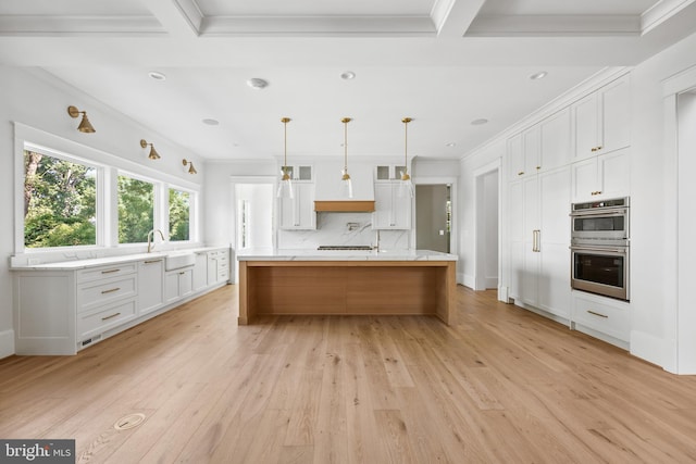 kitchen featuring a large island, stainless steel double oven, decorative light fixtures, decorative backsplash, and white cabinetry