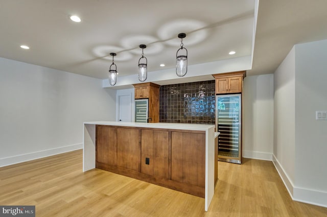 kitchen with light wood-style floors, brown cabinets, decorative light fixtures, and beverage cooler