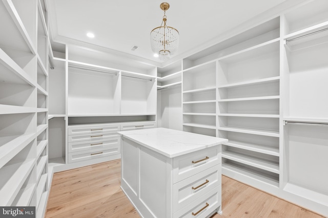 walk in closet with light wood-style flooring, visible vents, and a chandelier