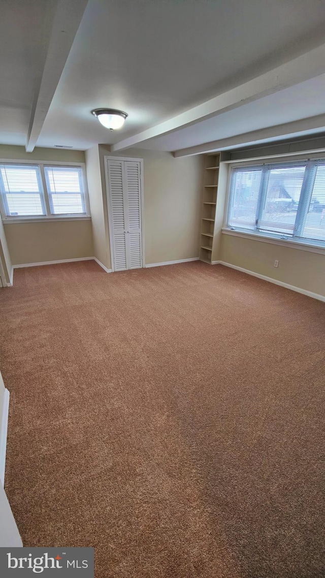 empty room with beamed ceiling and carpet flooring