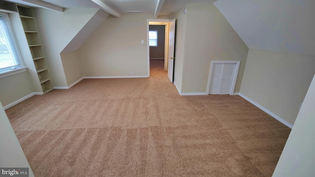 bonus room with vaulted ceiling with beams, light colored carpet, and built in shelves