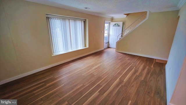 empty room with crown molding, dark wood-type flooring, and a textured ceiling