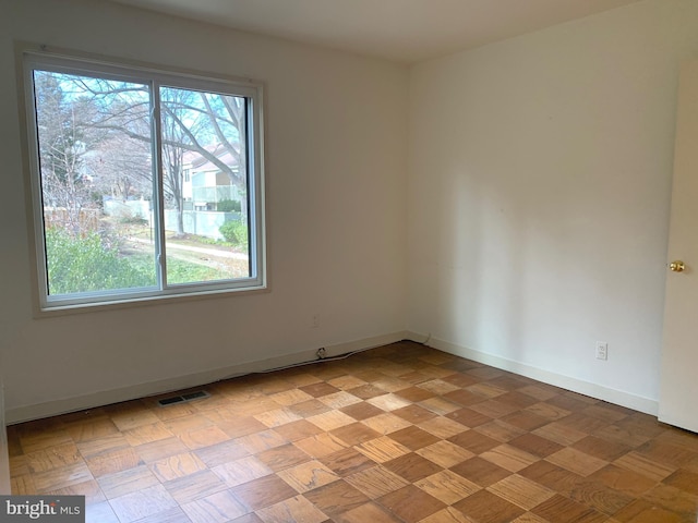 empty room with visible vents, a wealth of natural light, and baseboards