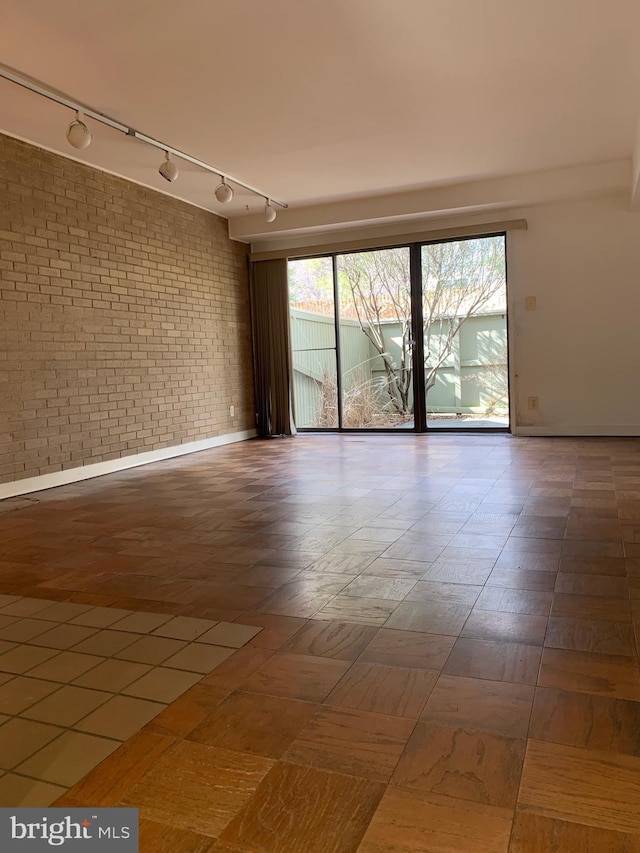 unfurnished room with a healthy amount of sunlight and brick wall