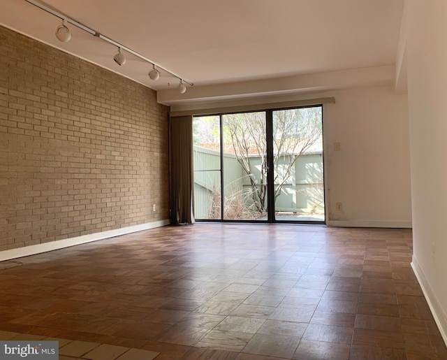 spare room featuring brick wall and baseboards