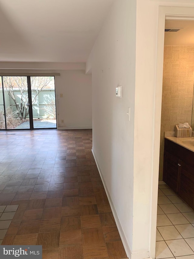 corridor featuring visible vents, a sink, and baseboards