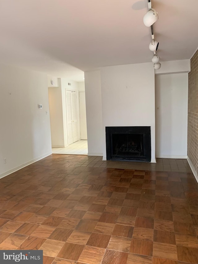 unfurnished living room with a fireplace with flush hearth and baseboards