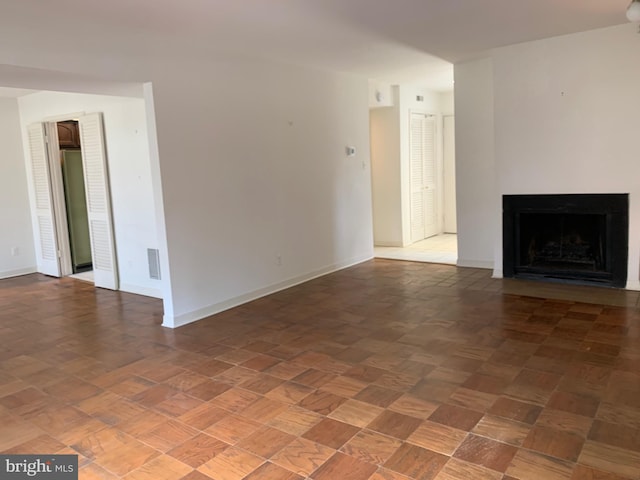 unfurnished living room with a fireplace, visible vents, and baseboards